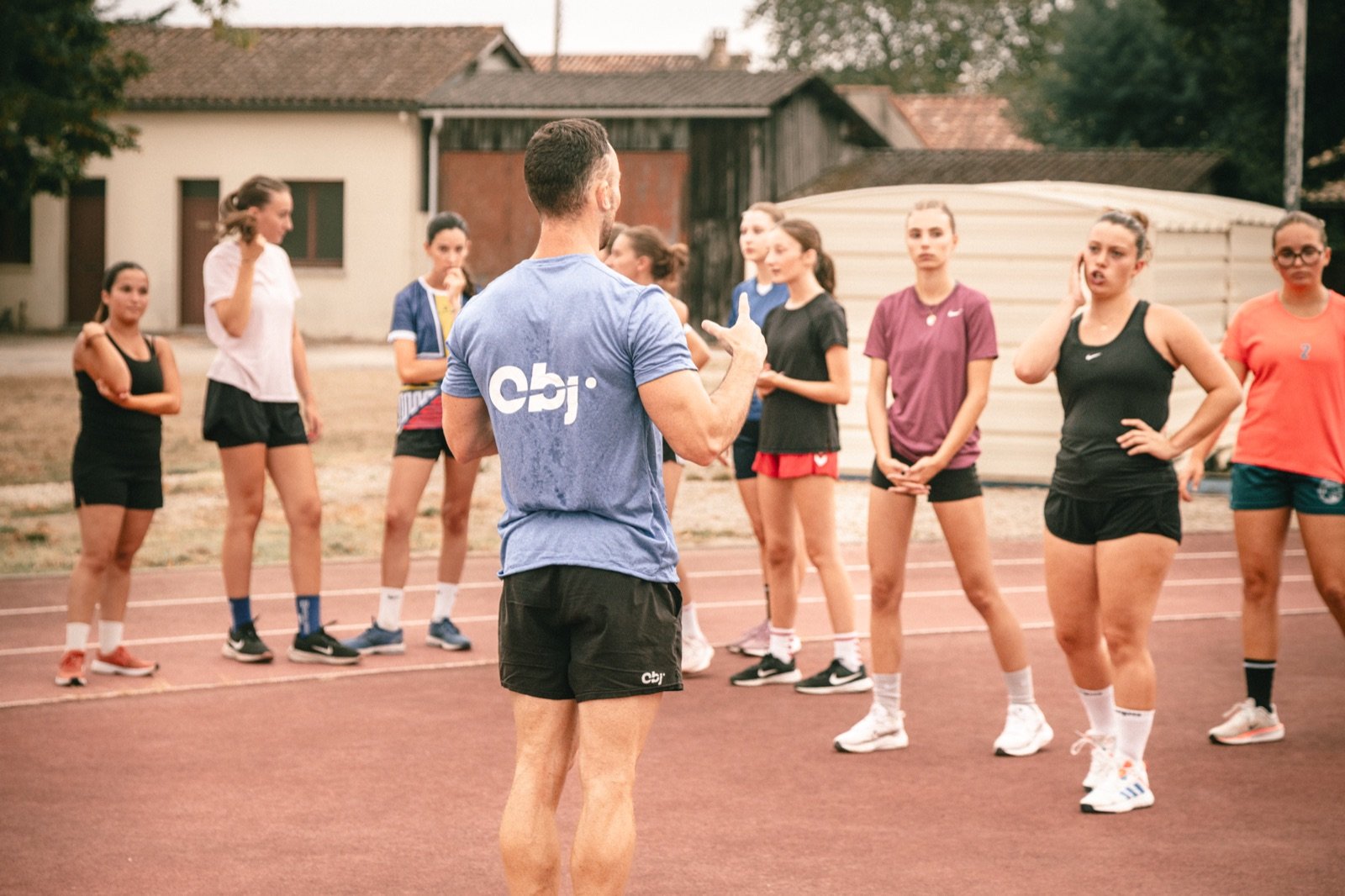 Coach s’adressant à son groupe pendant un entraînement en extérieur.