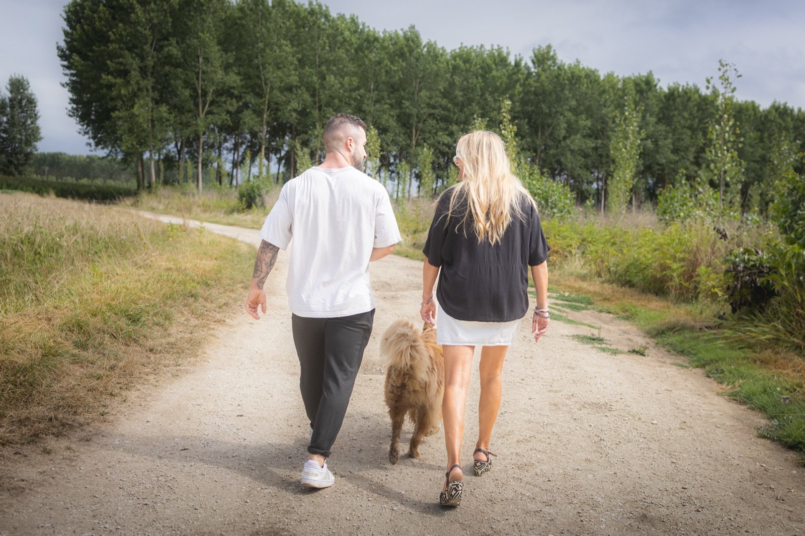 Deux personnes marchant sur un chemin de campagne avec un chien.